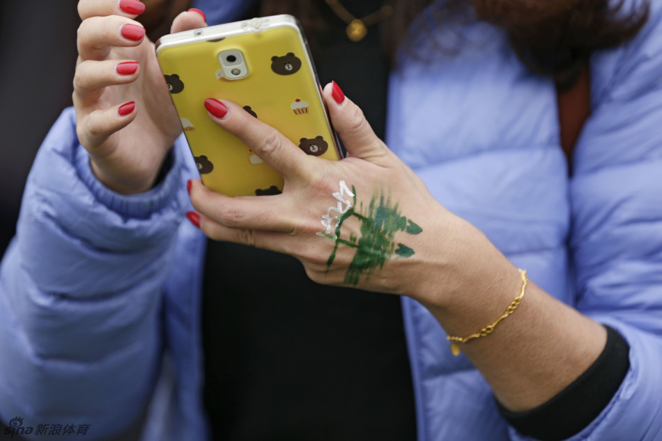 小女孩俏皮地模仿拉弓射箭的动作，脸上灿烂的笑容与她面颊的彩绘一样耀眼