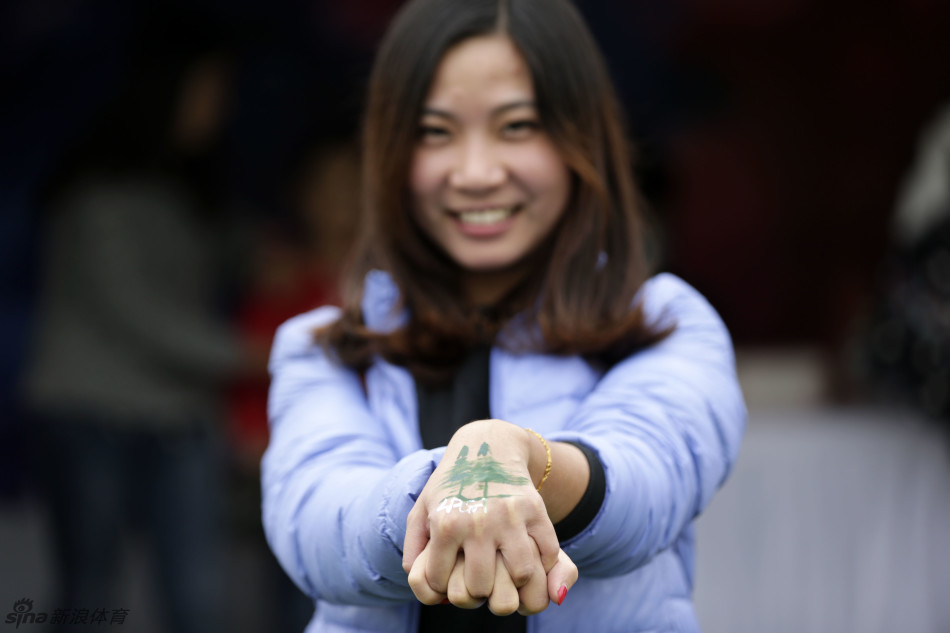 一位女士微笑着展示她手臂上刚完成的大面积彩绘，图案复杂而华丽，吸引周围目光