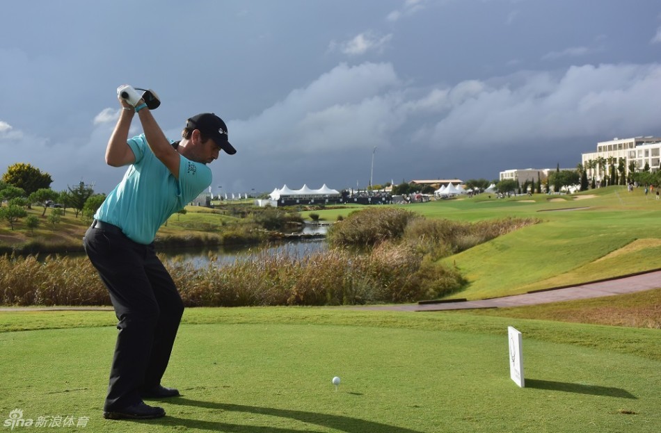 法国球员亚历山大·列维在雨中撑着伞走向下一个击球点，神情专注，步伐坚定。