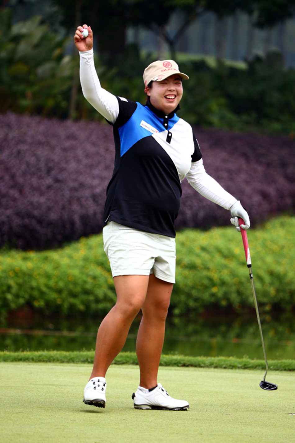 冯珊珊向观众展示冠军奖杯，身后是飘扬的国旗与欢呼的人群