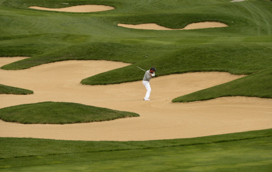 白托德从沙坑中成功救球，沙砾飞扬，他正专注地目送小球飞向果岭