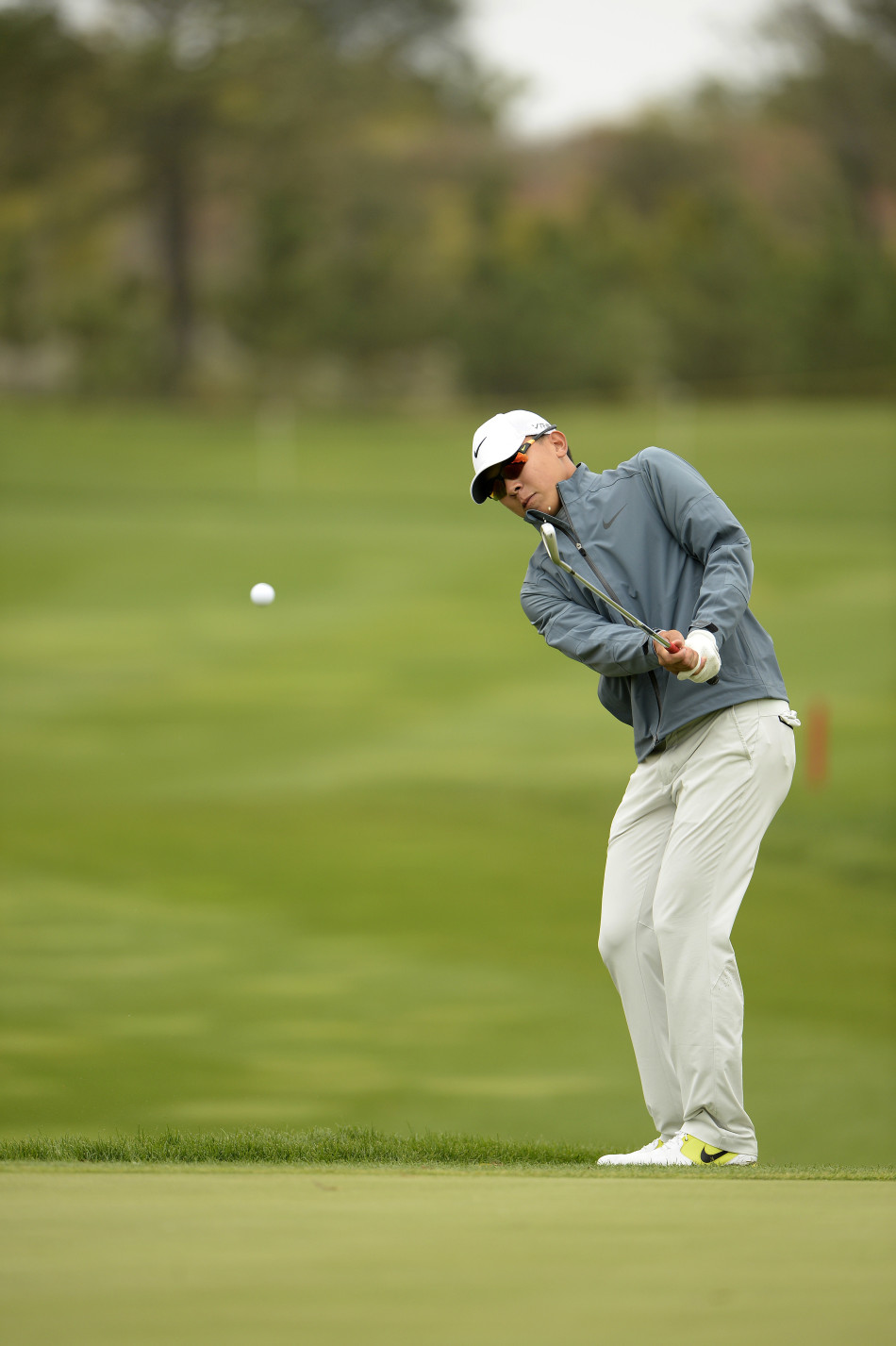 陈子豪在沙坑中调整站位准备击球，阳光洒下勾勒出他专注的侧影