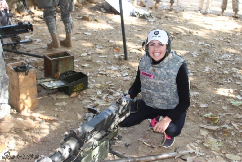 克里默坐在桌前,手持粉色签名笔,正微笑着为一位年轻士兵在纪念品上认真签名,周围士兵眼中充满期待。