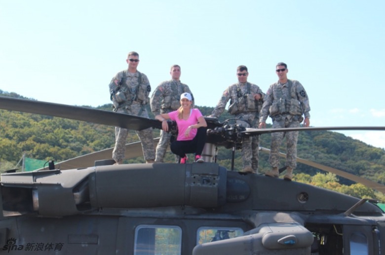 克里默在军营帐篷外,好奇而认真地观察并尝试操作一挺重型机枪,她的表情里充满了学习新事物的专注。