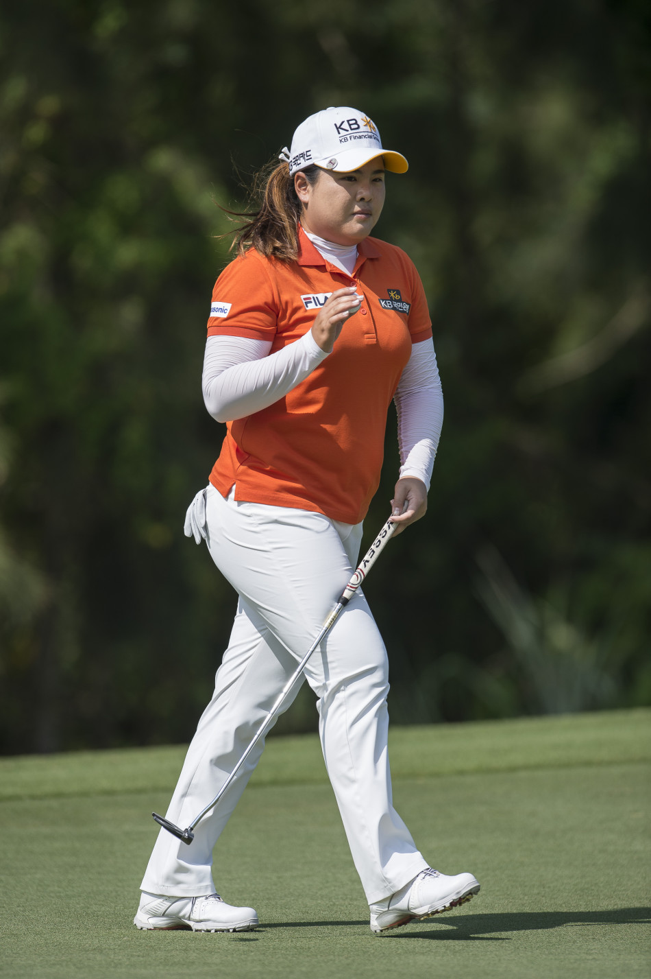 朴仁妃在球道上手持推杆前行，步伐坚定自信