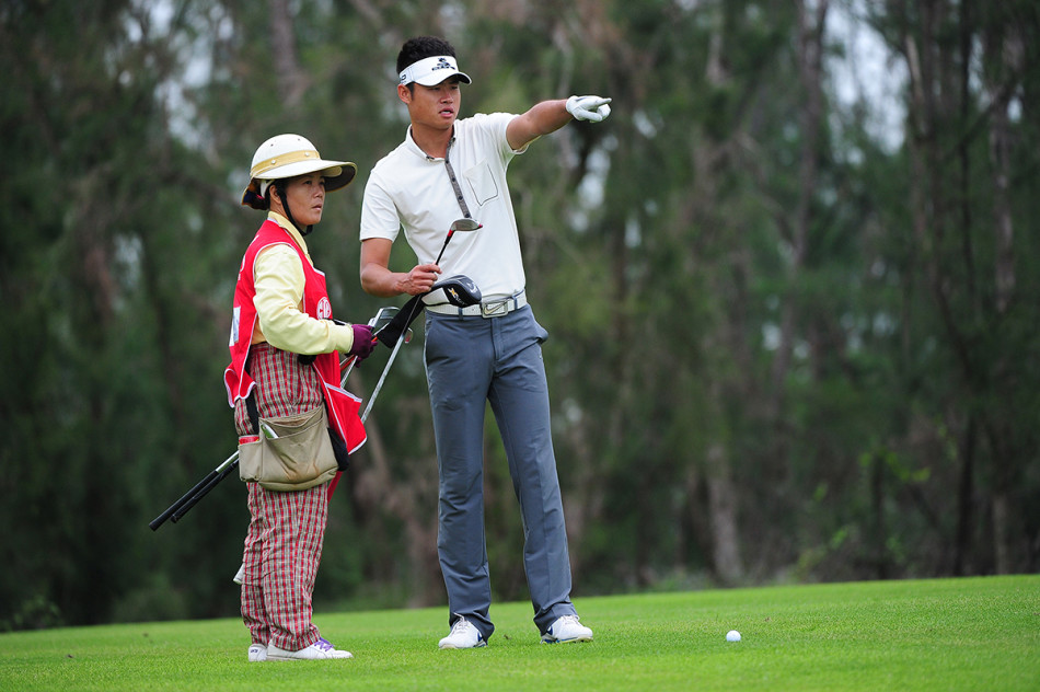 黄光典与他的伙伴在球场边交流，后者正用手指着远方，两人之间流露着信任与轻松的氛围。