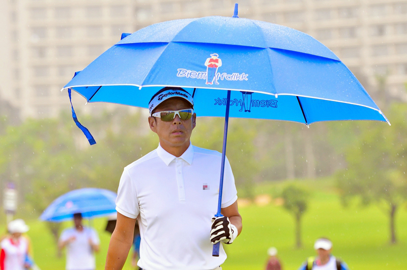 陈道明身着黑色雨衣于细雨中沉稳挥杆，目光如炬尽显大师风范