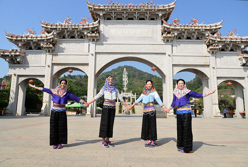 法国球手乔安娜身穿蓝印花布惠安女服饰，优雅地整理着头上的斗笠，展现出异国风情与东方韵味的奇妙融合。