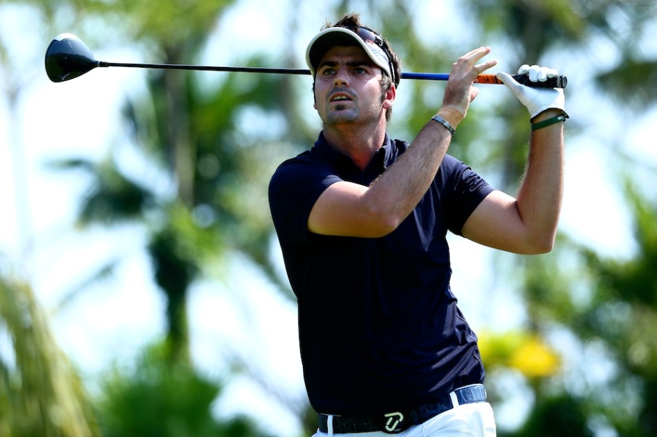 冠军球手布雷特·德维特与他的球童在果岭边微笑交流，他们的手中或许正握着那顶具有纪念意义的帽子，眼神中充满了共享成就的默契。