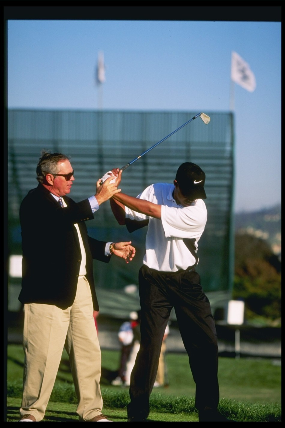 哈蒙手指远方，似乎在为伍兹讲解球场策略，伍兹顺着方向望去，两人如同战场上的将领在研究地形。