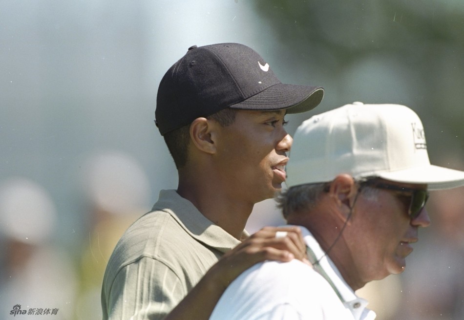 赛场之上，伍兹凝神准备推杆，哈蒙在观众群中静静驻足观看，眼中充满期待与信任。