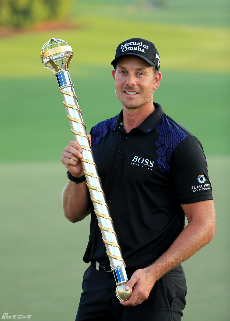 斯滕森在球迷的簇拥下高举冠军奖杯，阳光洒在银杯上，映照着他灿烂的笑容。