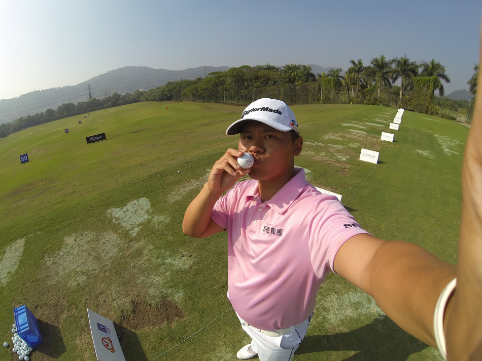 林冠伯在果岭上蹲身凝视球线，神情专注，身后是宽阔的赛场，一场精彩的较量即将展开。