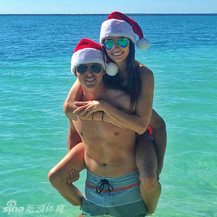 里奇·福勒与女友在贝克海滩的圣诞夕阳下甜蜜相依，浪花与余晖环绕着幸福的恋人。