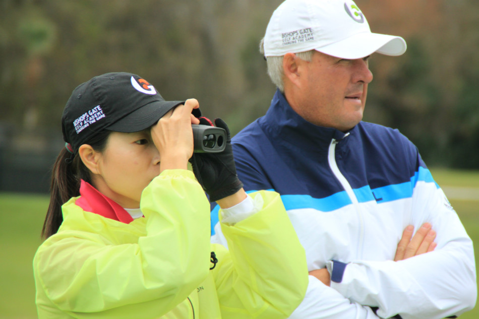 教练正详细记录球员的球杆规格数据，为个性化的球具调整提供依据