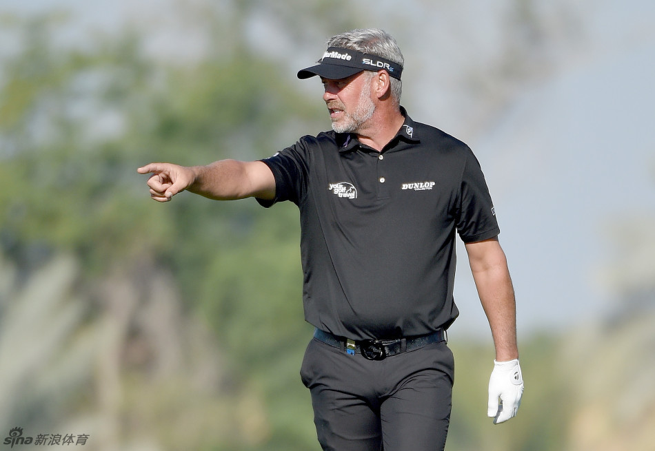 高尔夫球手在发球台专注地进行开球准备，背景是开阔的球场与远山