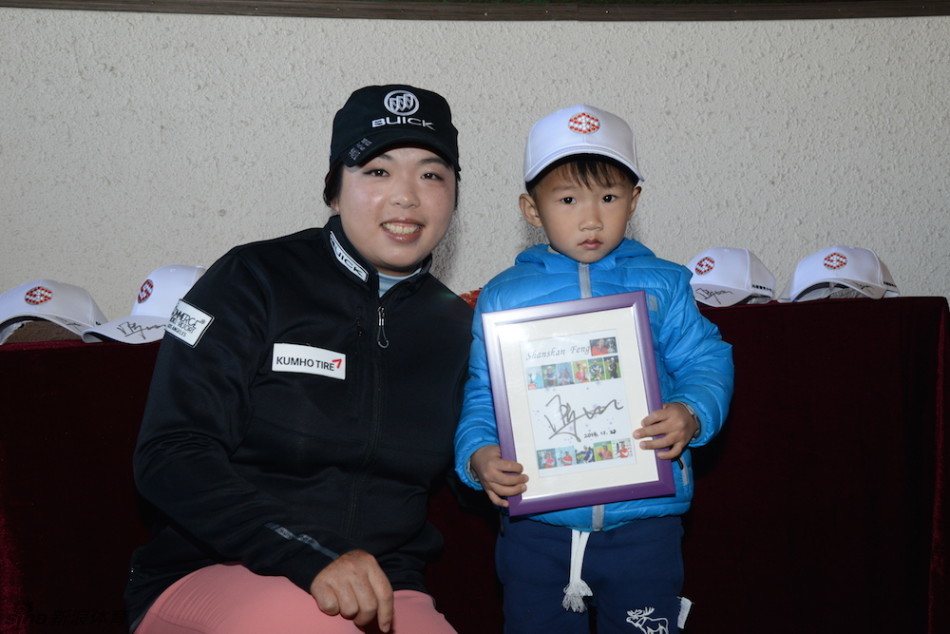 室内高尔夫模拟器前，一位青少年在冯珊珊的注视下进行推杆练习，屏幕上的虚拟球场画面栩栩如生。