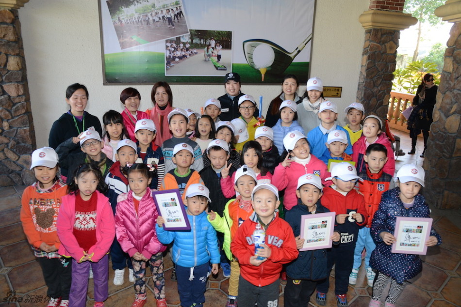 一群参加校园高尔夫项目的孩子，在果岭练习区成功推球入洞后，兴奋地击掌庆祝。