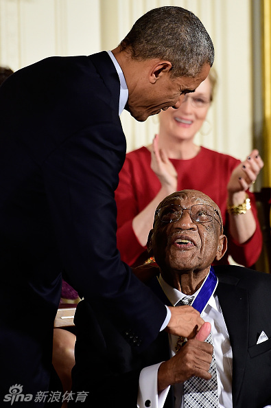 白宫授勋典礼现场全景，斯福德与其他获奖者一同站立，奥巴马总统正在致辞，场面隆重而充满敬意。