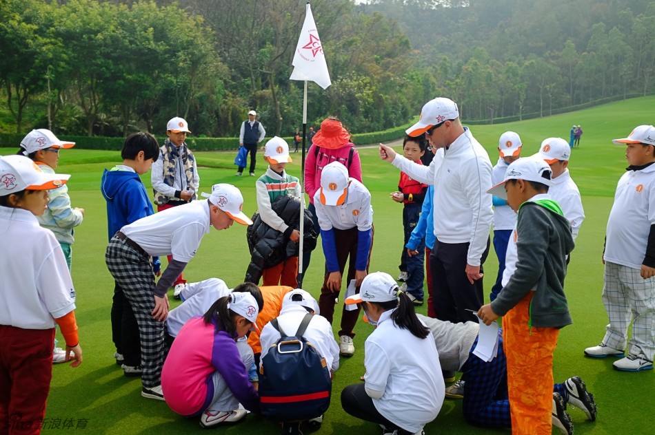 教练与选手一同蹲在果岭边，手指指向洞口，深入探讨推杆的线路与力度秘密