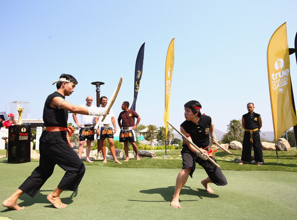 国际高尔夫球星们围坐在拳台边，全神贯注地观看一场精彩的泰拳表演