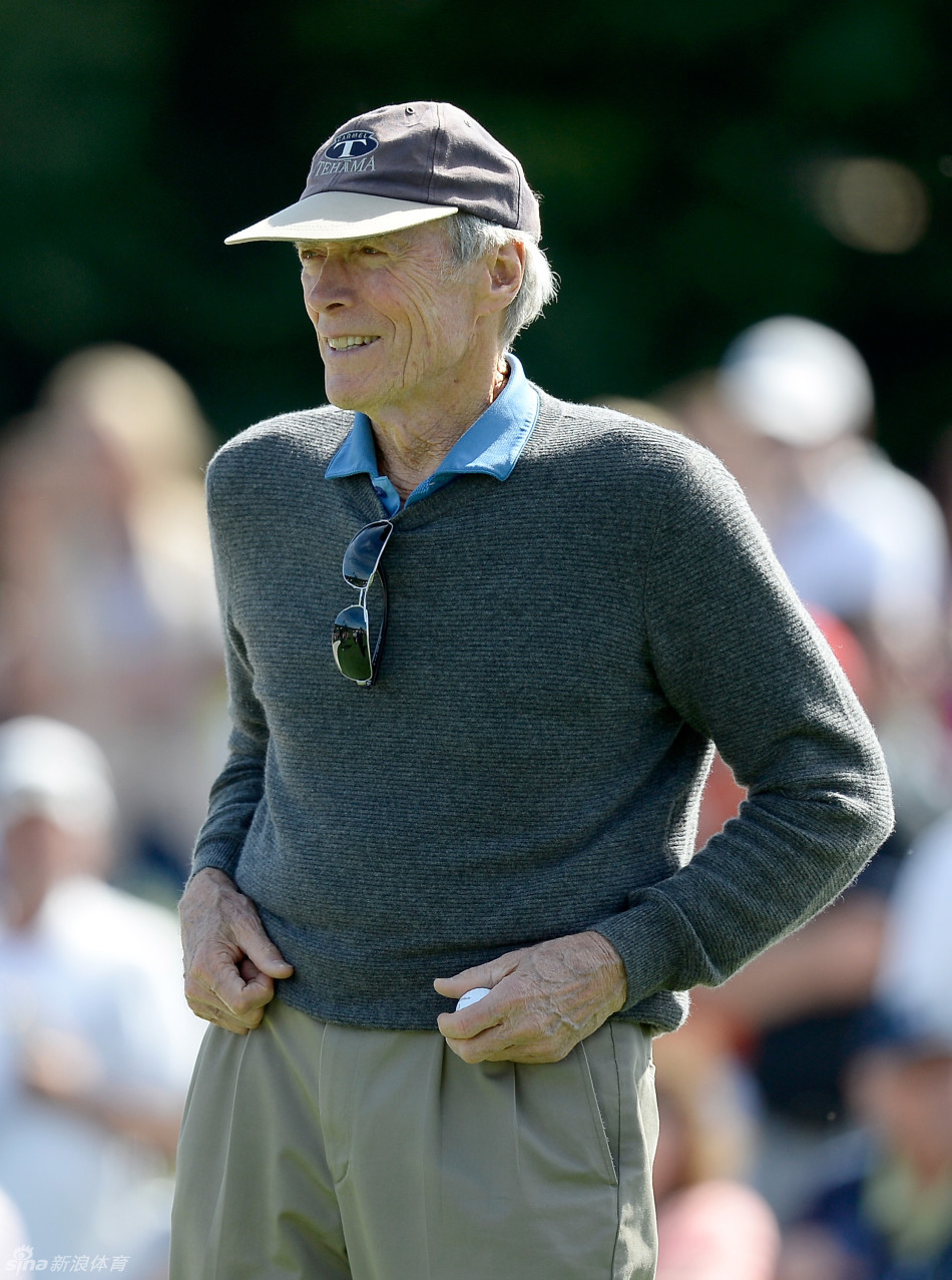 达斯汀·约翰逊在开球区准备击球，背景是郁郁葱葱的树木和晴朗的天空