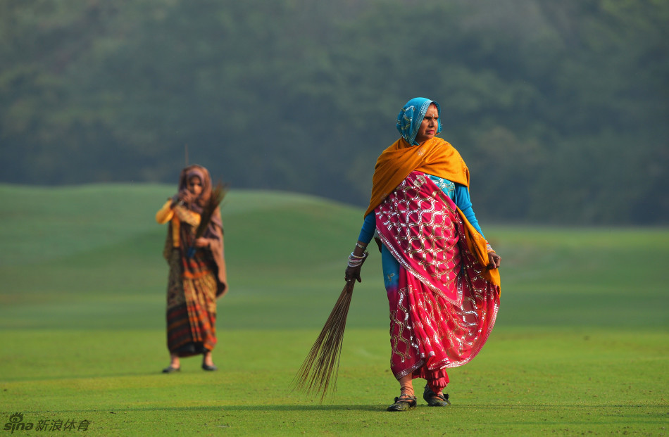 夕阳西下,高尔夫球场的湖泊水面倒映着霞光与树木,一名球手正在岸边准备击球,景色如画