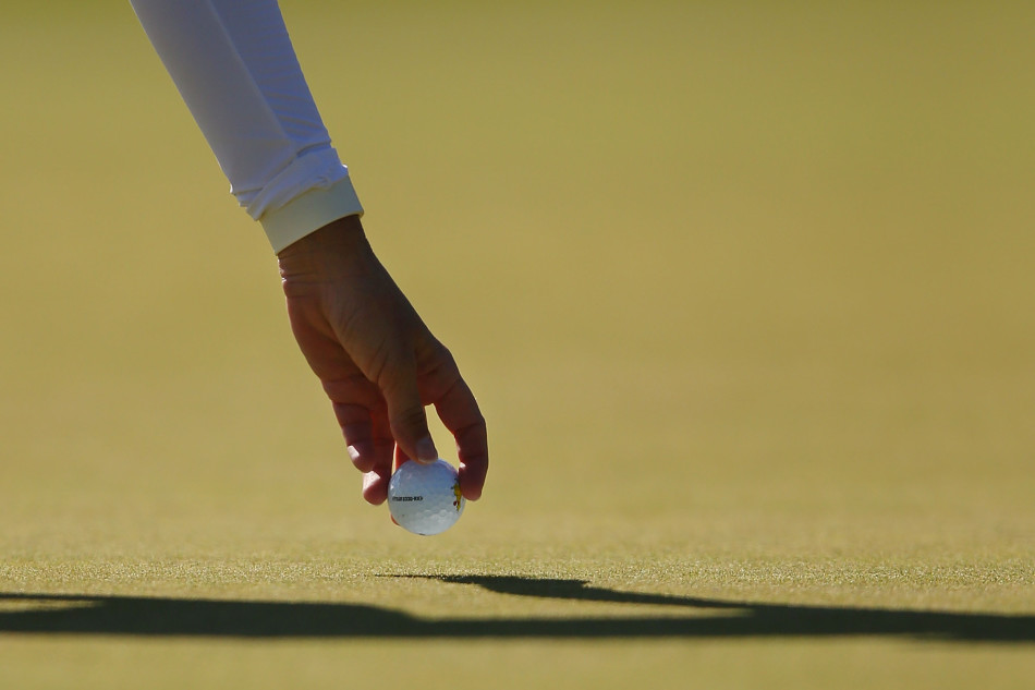 挪威女将玛丽安娜与她的球童并肩观察球场，共同谋划下一杆的策略。