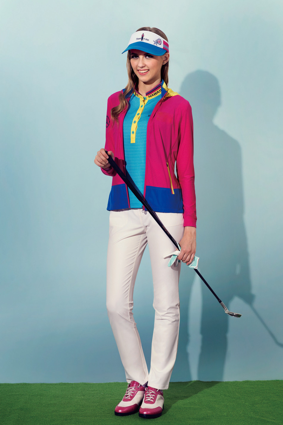 模特身着宝蓝色宽松高尔夫POLO衫,在果岭背景下舒展双臂,面料轻盈随风微动,尽显运动剪裁的自由度与活力