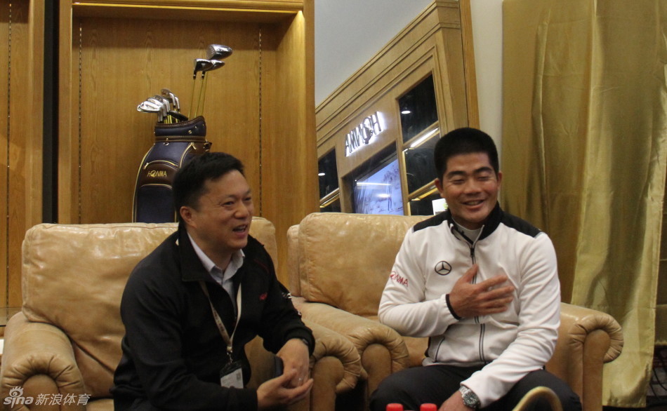 梁文冲与品牌工作人员合影留念，背景是品牌标志，展现紧密合作关系