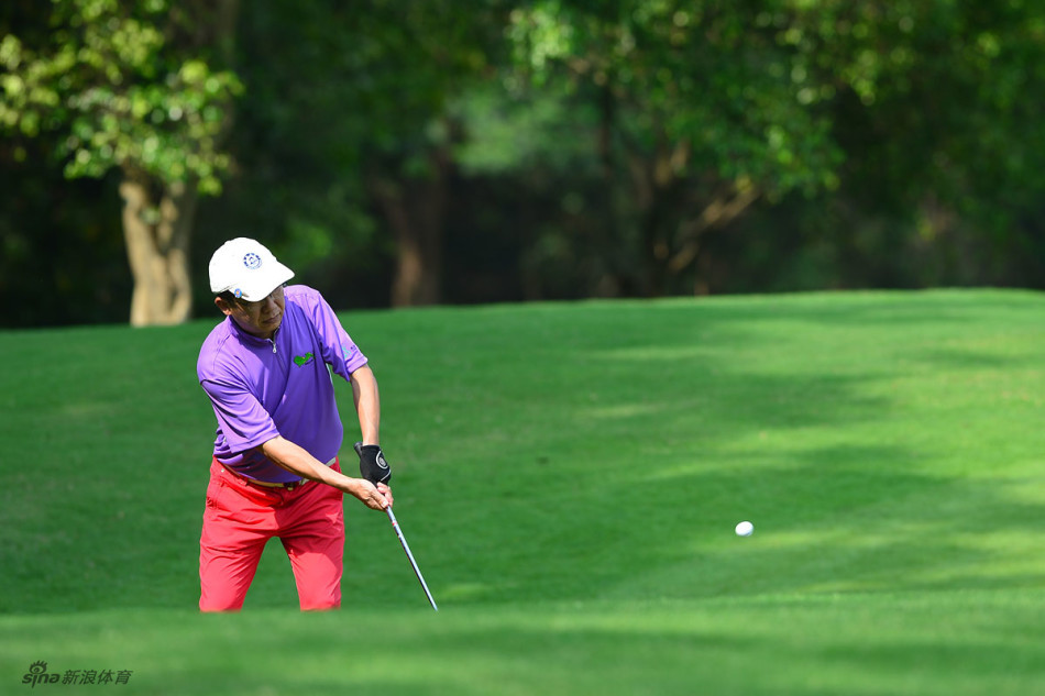 球员在果岭边精细切杆，全神贯注于球的飞行路线与落点，展现高超的短杆技巧。