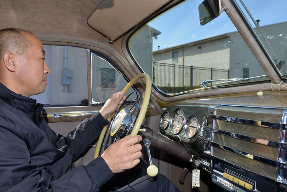 一张泛黄的别克老广告海报与一台车身锈蚀、等待重生的经典车骨架并列放置,形成一种跨越时空的强烈对话。