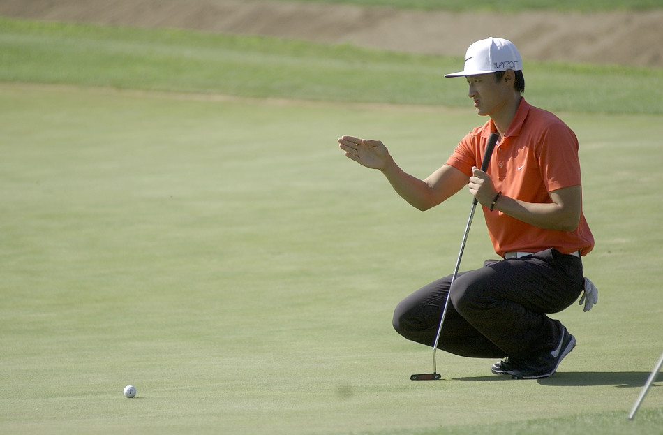 李昊桐在发球台上完成大幅度的全力挥杆，红色上衣在翠绿草地的映衬下如火焰般跃动，动作流畅而充满力量，球杆划破空气的瞬间被完美定格。