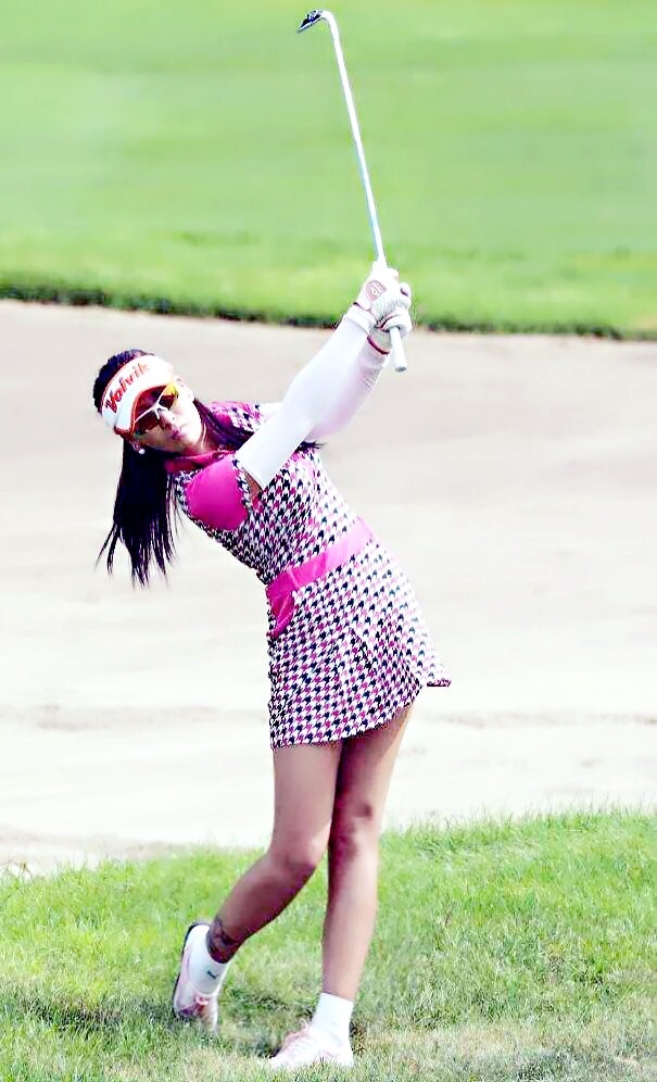 杨欣颖手持高尔夫球杆,在绿茵场上做出专业挥杆姿势,动静皆宜