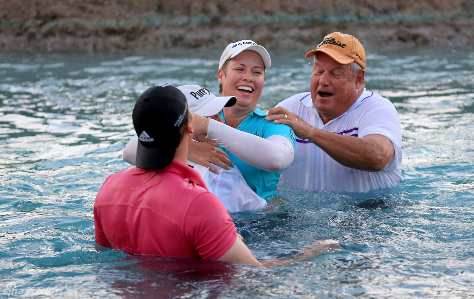 冠军与球童在观众雷鸣般的欢呼中携手跃入波比池，溅起象征胜利与欢乐的巨大水花