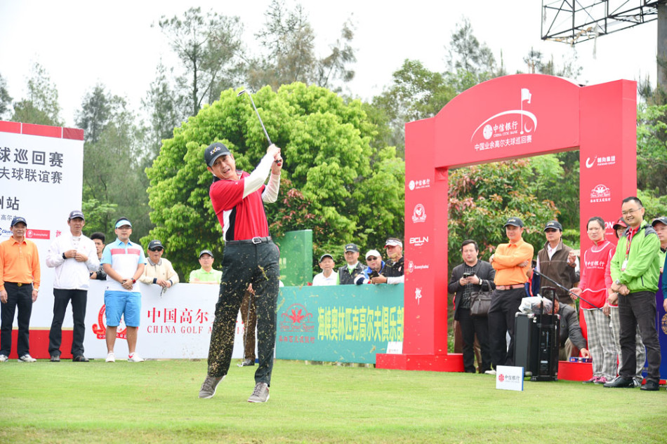 活动结束后众人手持奖杯与球杆在俱乐部会所前合影,身后是海峡奥林匹克高尔夫俱乐部的标志