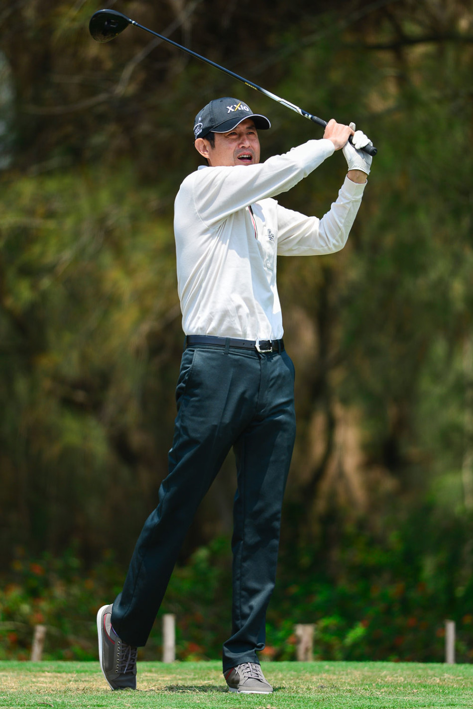 林丁山在晨光中面带微笑,手持挖起杆准备进行果岭边的切杆练习,专注的眼神投向远处的球洞