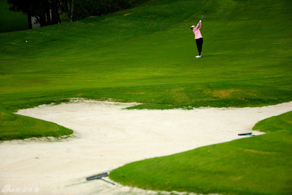 绿草如茵的球道上，两位球员与一位教练正在轻松交流，氛围融洽，体现了高尔夫运动教学相长、共同进步的传统。
