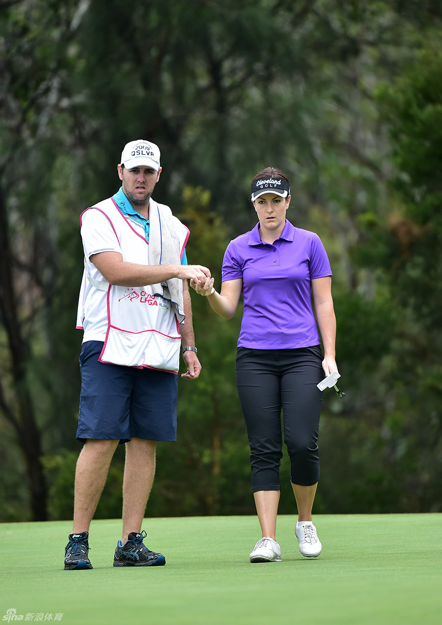 里奇·加勒特在开球前进行最后的准备，她的侧影在阳光下显得坚定而柔和，展现了运动员与母亲双重身份的美妙融合。