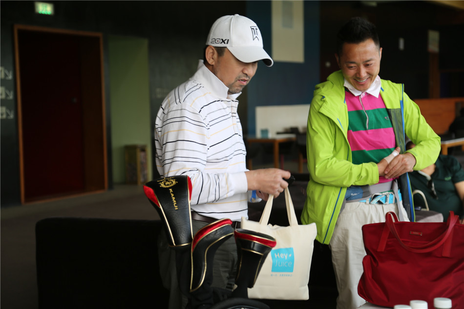 两位女球员在球场边亲切交谈，她们手持球杆，似乎正在分享某个球洞的打法心得，展现了运动中的友谊与交流。