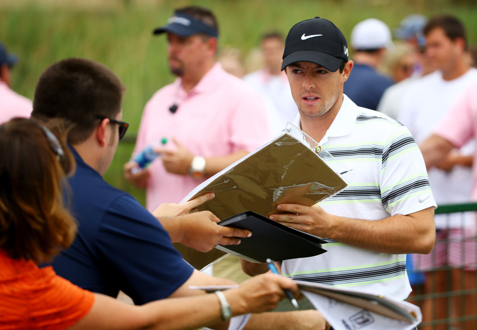 罗里·麦克罗伊微笑着满足一位小球迷的签名请求,展现巨星的亲和力