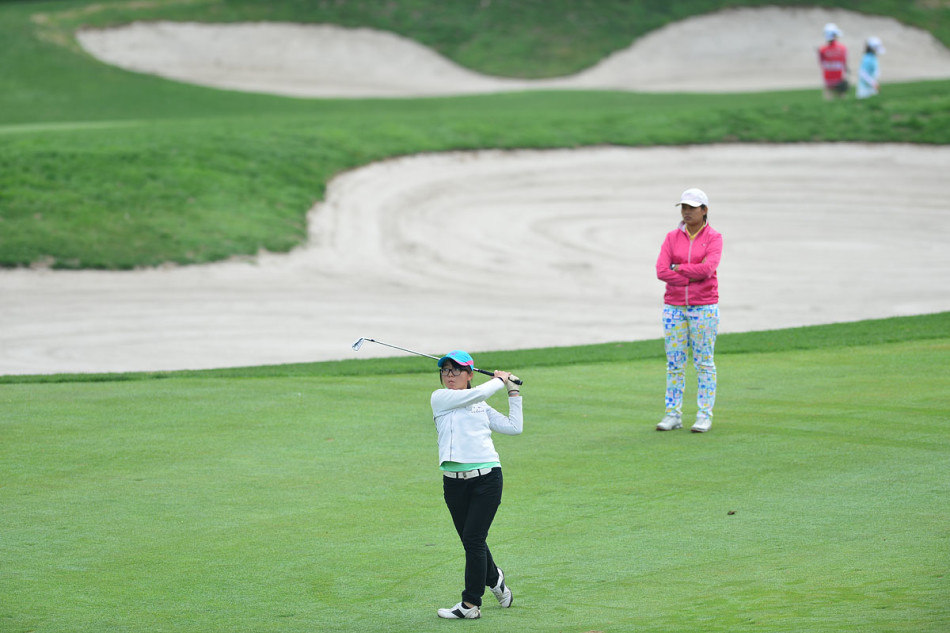 球员在果岭上单膝跪地，手指轻触草皮，正极其认真地解读地面的起伏与推杆线路