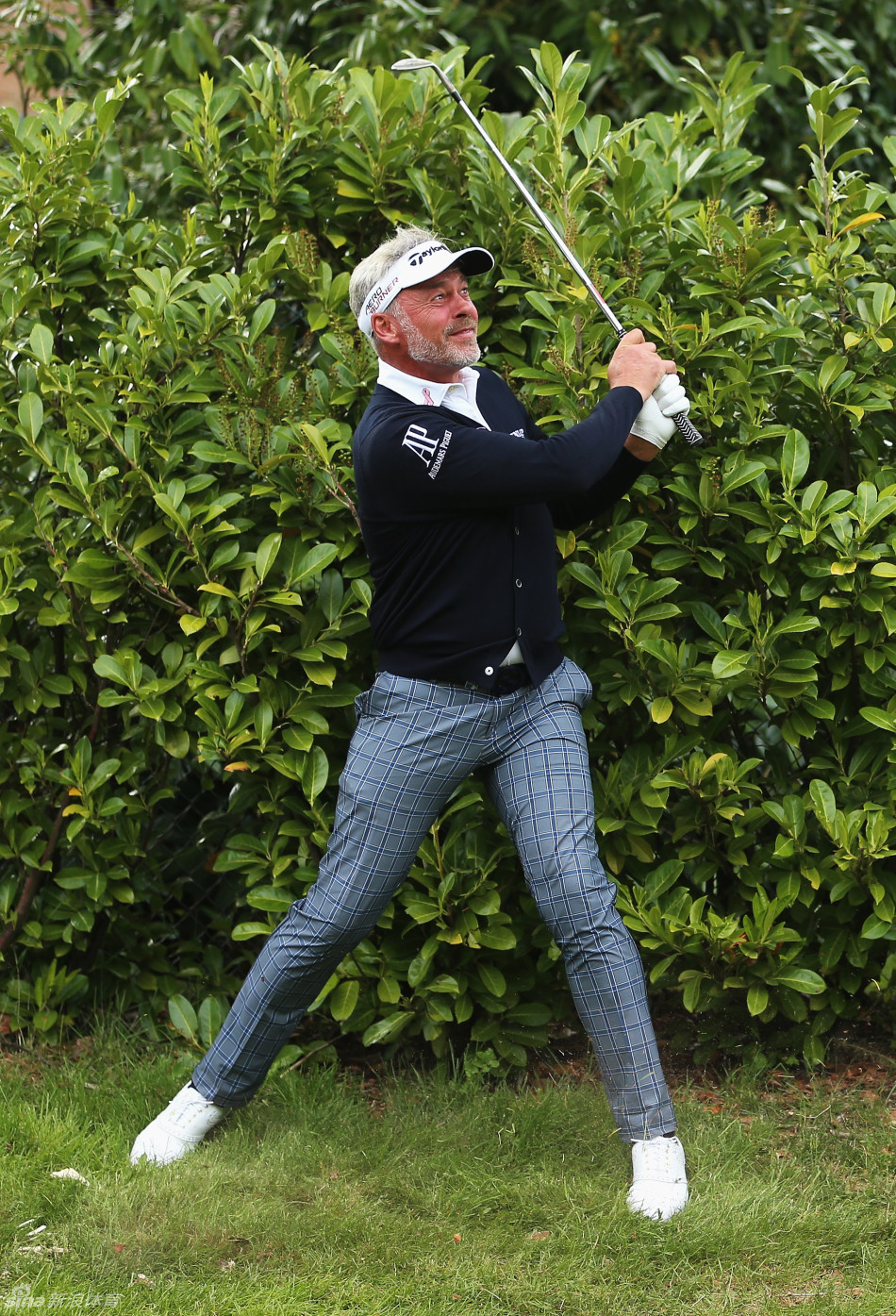 一位球童正蹲在托里松林巨大的果岭边，为球员仔细擦拭高尔夫球，果岭起伏的曲线与远处宁静的球场形成一幅专注而专业的赛场景象。