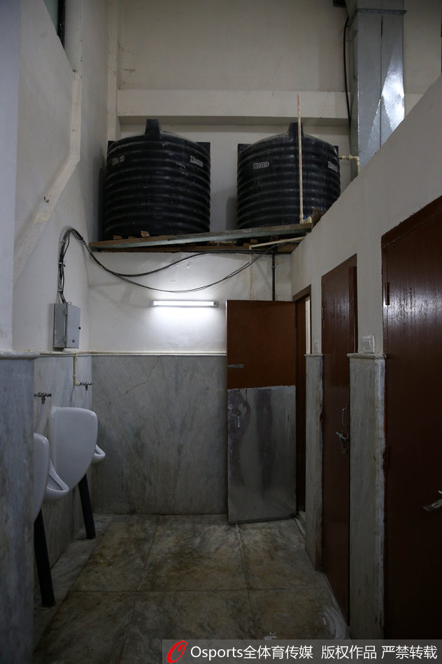 略显空荡的房间里，长椅上散落着国家队的红色战袍，窗外透进的光束照亮了地面，仿佛照亮了那个年代中国足球在简陋条件下依然奋力前行的足迹。