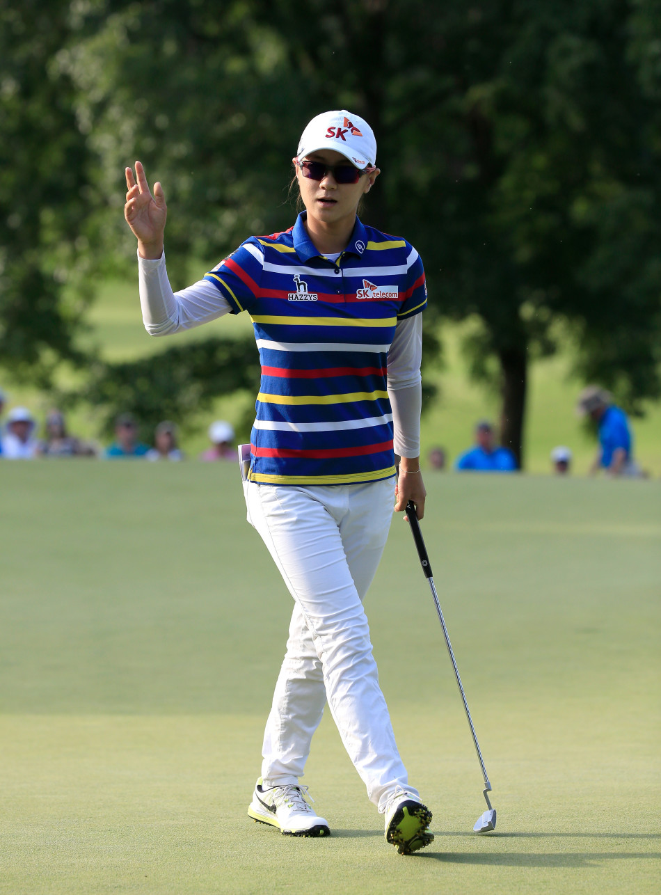 崔罗莲在果岭上单膝跪地，仔细观察推杆线路，表情沉着冷静