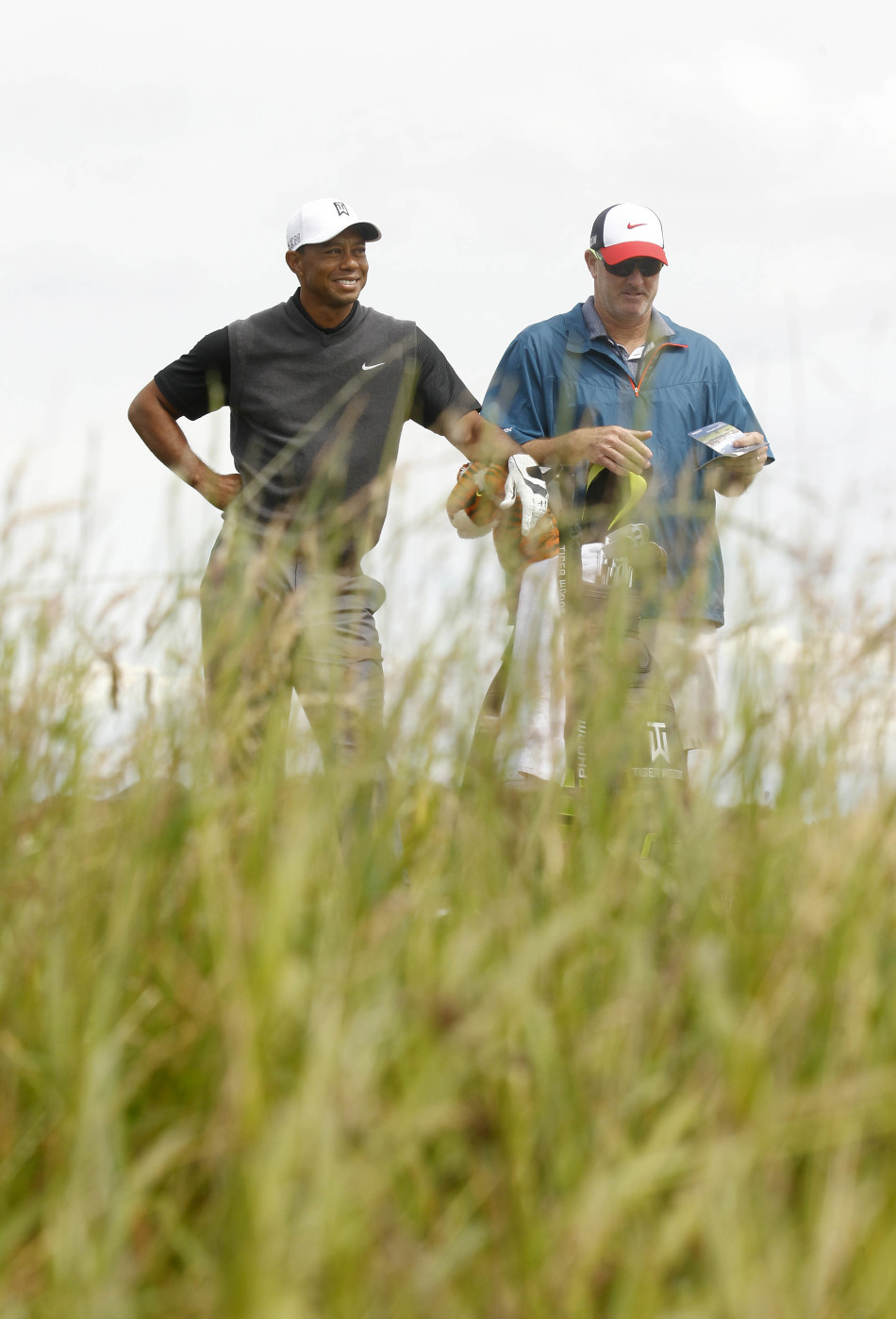 伍兹与球童并肩走在如画的球道上，两人手指远方热烈讨论战术，展现出无间的信任与专业。