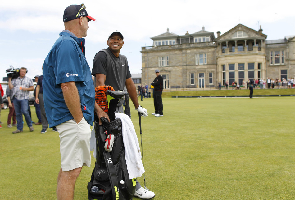 黄昏下的圣安德鲁斯老球场全景，伍兹的背影走向远方，与宏伟的历史建筑融为一体，充满故事感与传承意味。