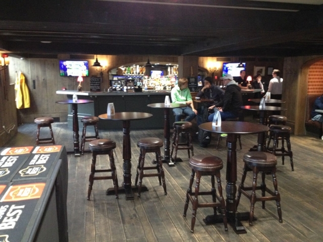 酒馆内部一角，温暖的灯光洒在深色木质桌椅和老旧的高尔夫纪念品上，氛围温馨怀旧