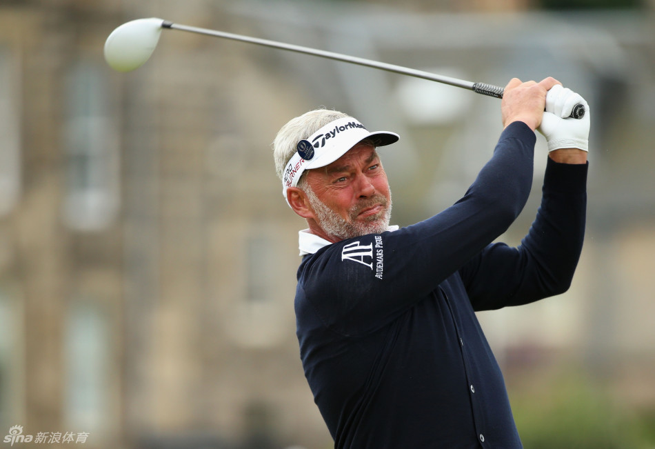 达伦·克拉克在风中眯眼审视球路，花白的胡子刻着岁月的痕迹，手中的球杆紧握，展现出历经沙场的老将专注与决心。