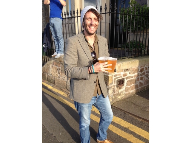 一群朋友围站在一张小圆桌旁畅饮，桌面上摆着好几品脱啤酒，众人皆开怀大笑，仿佛大雨带来的不是困扰，而是额外的乐趣。